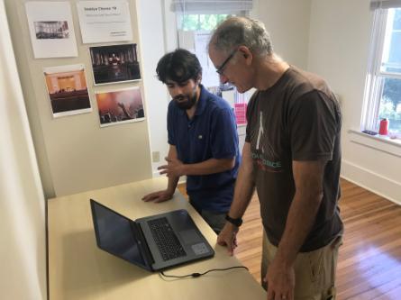 Saadya Chevan explains the computer program he is designing via mac computer to a parent who attended his project presentation