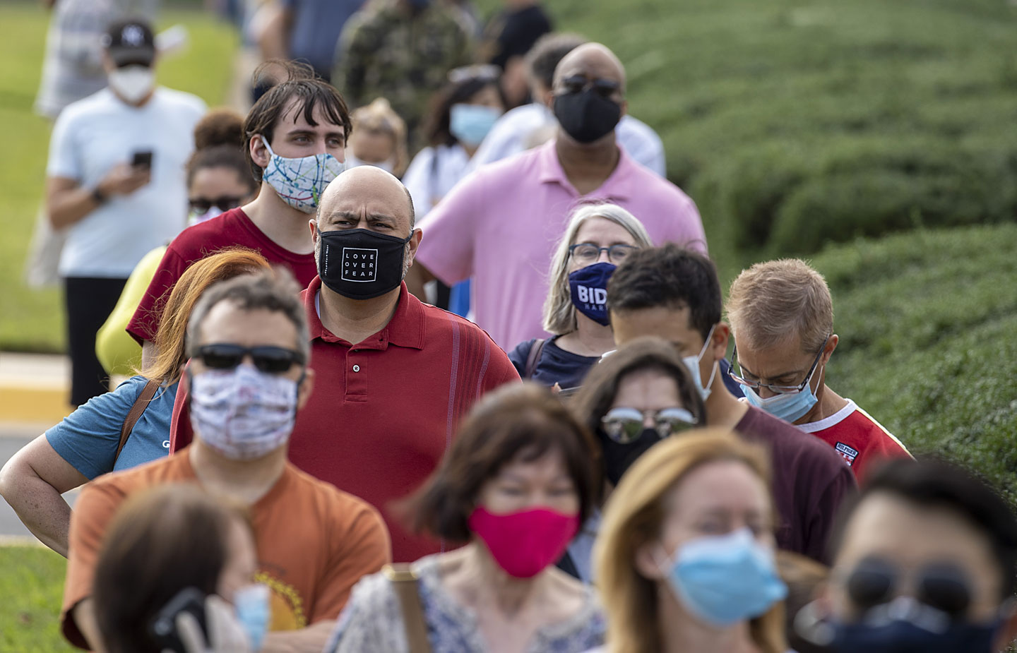 Image of people waiting in line to vote wearing masks