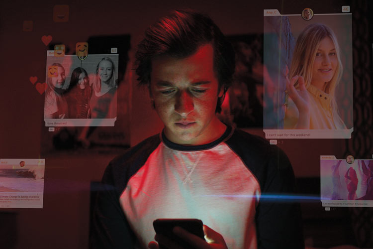 Image of young man looking at his phone in the dark