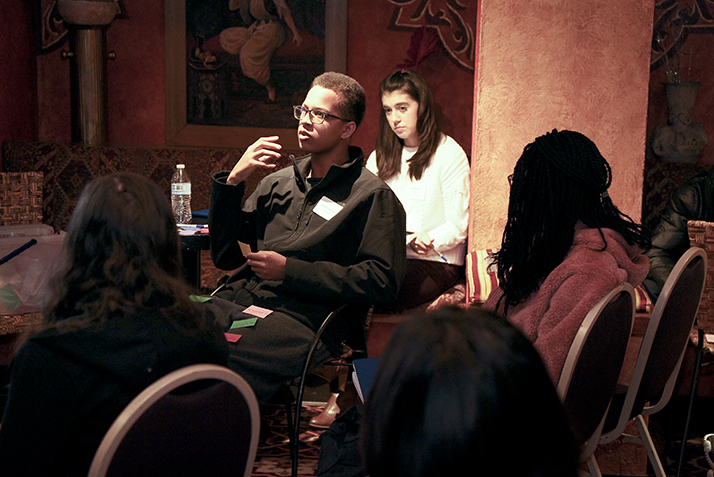 A student speaks as students at other tables look on.