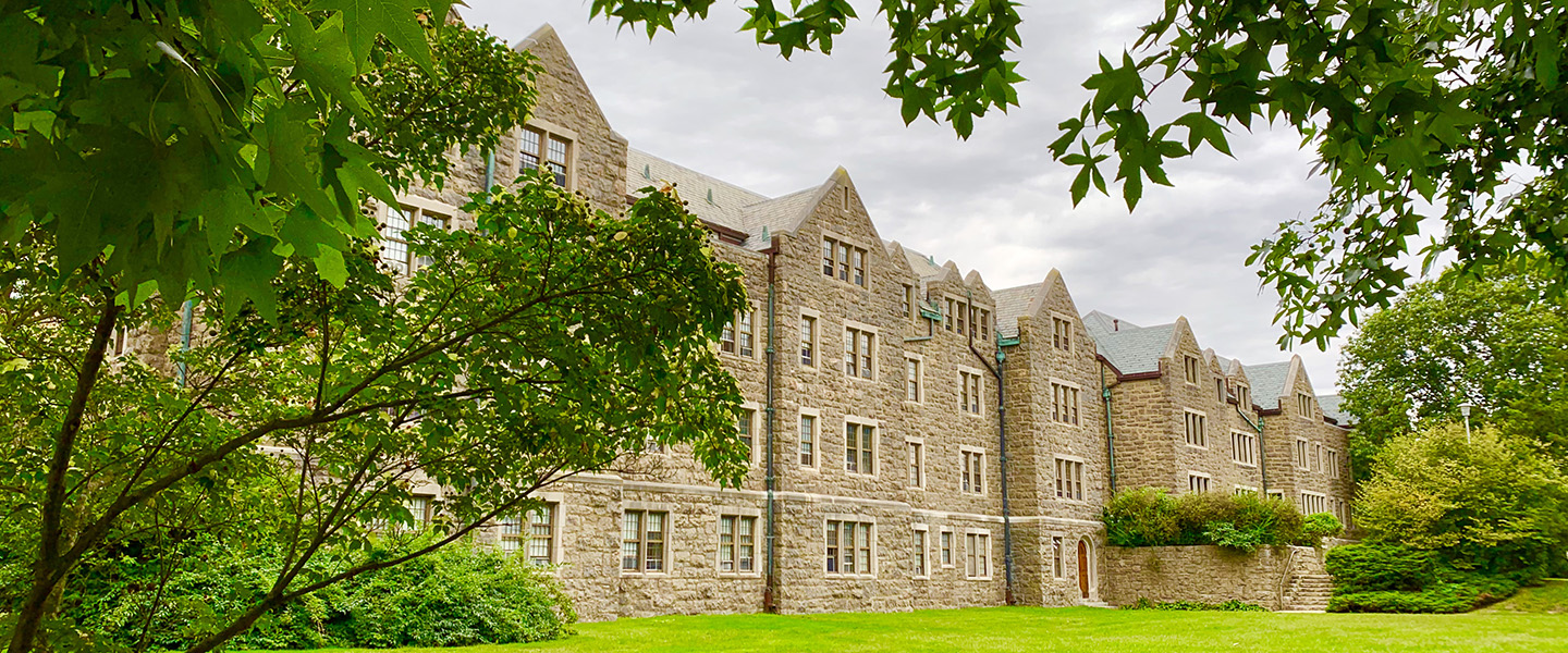 A student dormitory is framed by foliage. 