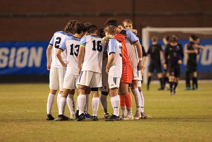 The players huddle on the field.