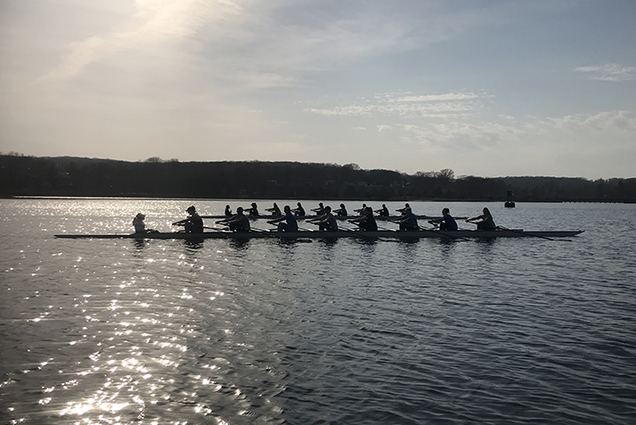 Rowers on the Thames River at dusk.