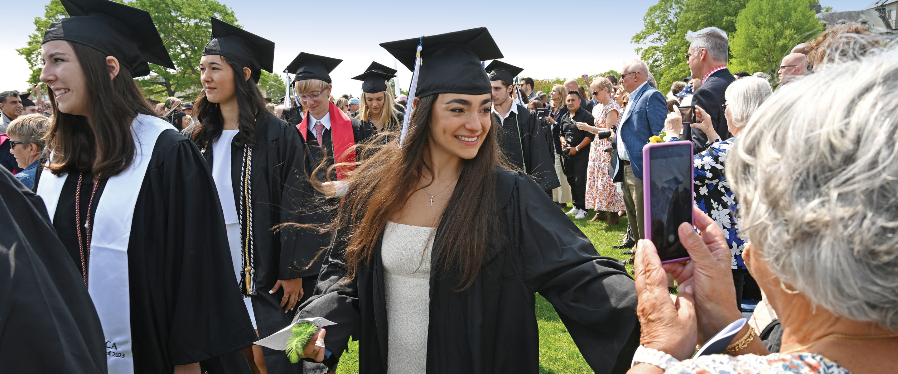 A relative takes a photo of a graduate during the procession.