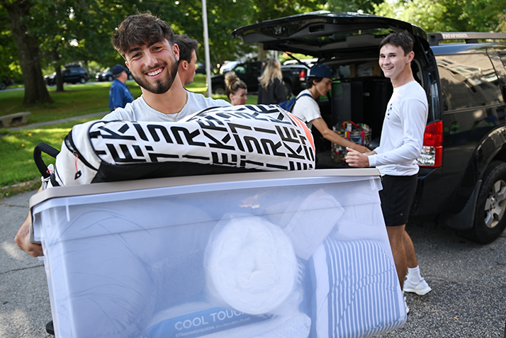 A student smiles as boxes are unloaded from the family car.