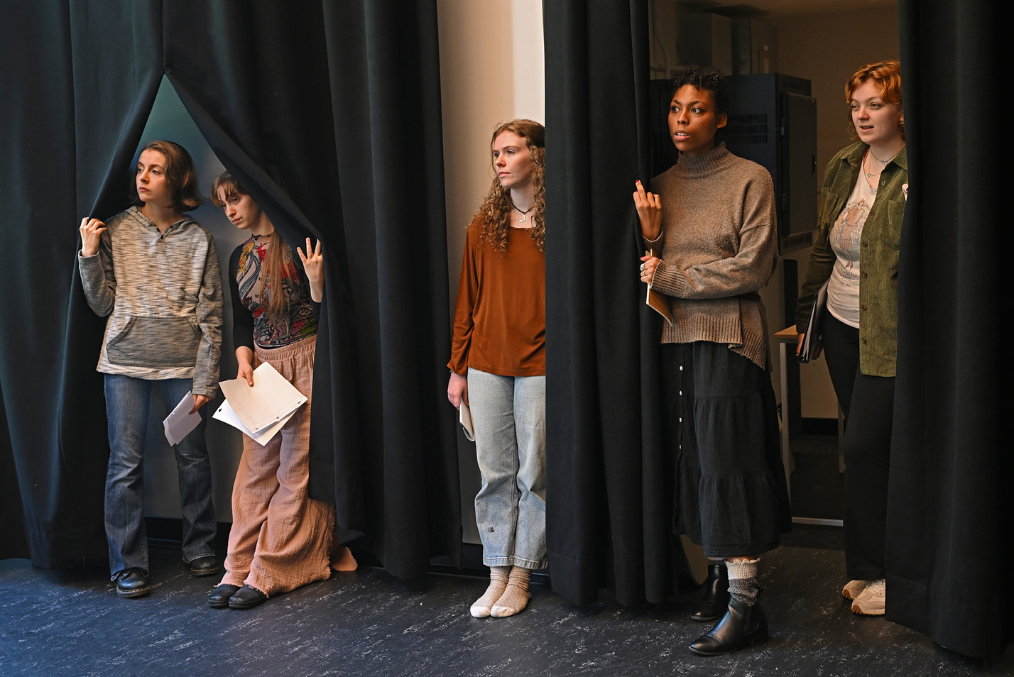 Theater students watch from the side of the stage