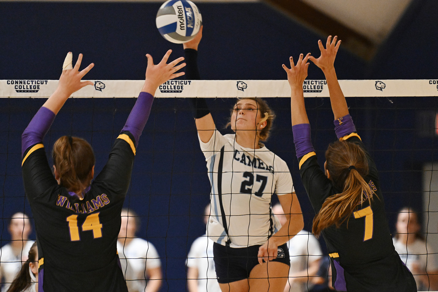 Volleyball player spikes ball over net