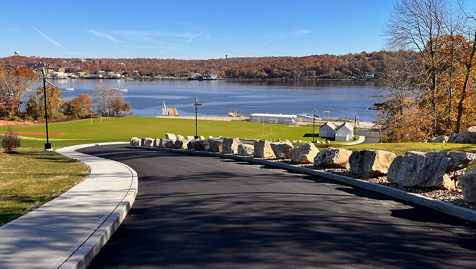 A photo of the new road, grass area, buildings and waterfront.