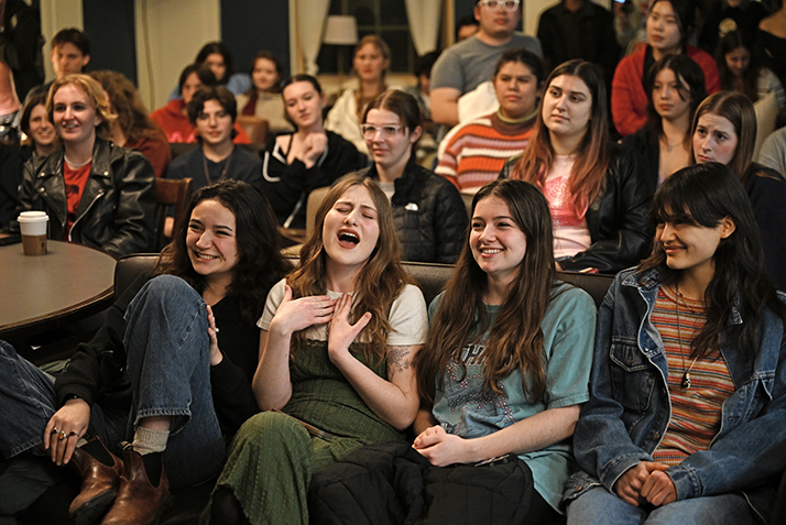 three seated students sing along with a rock band.