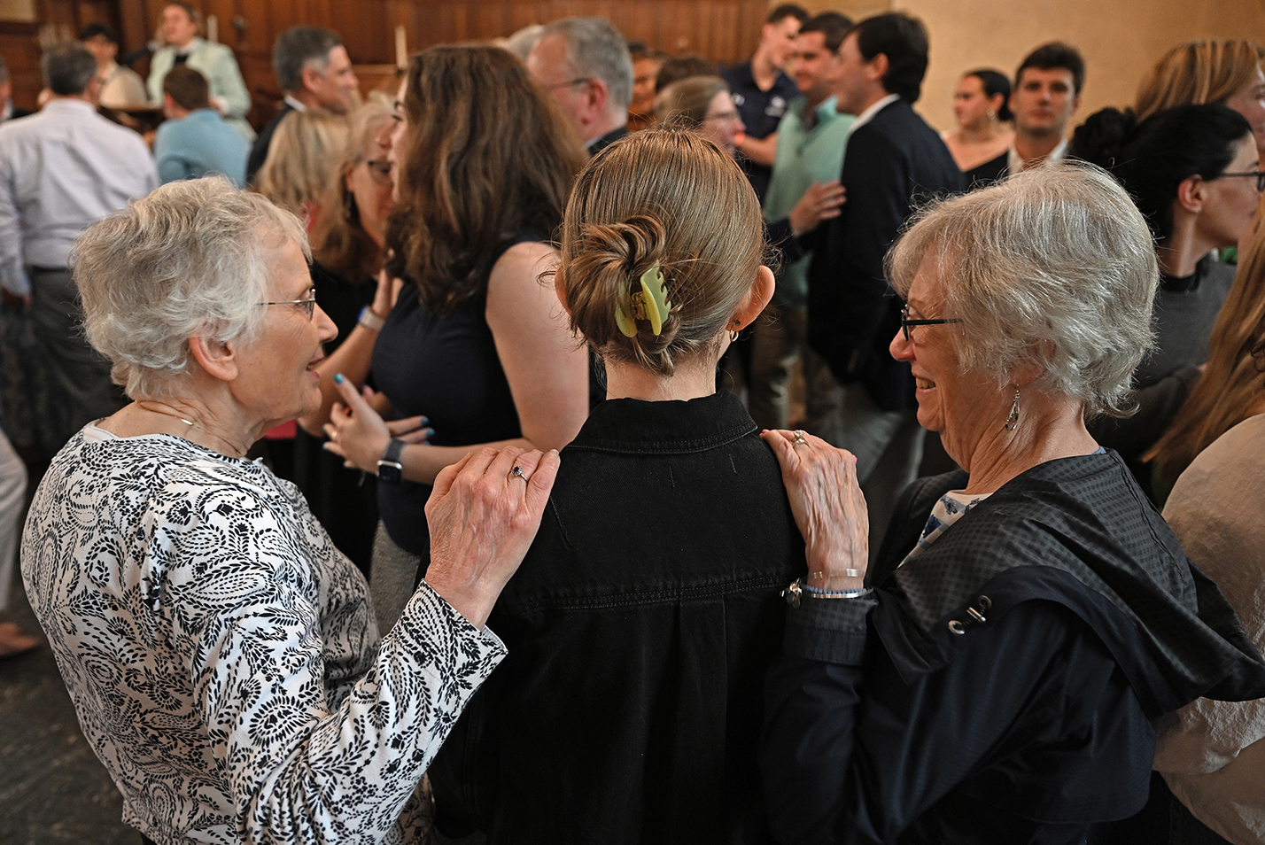 family members set their hands on the shoulders of a graduating senior during a blessing concluding a baccalaureate ceremony