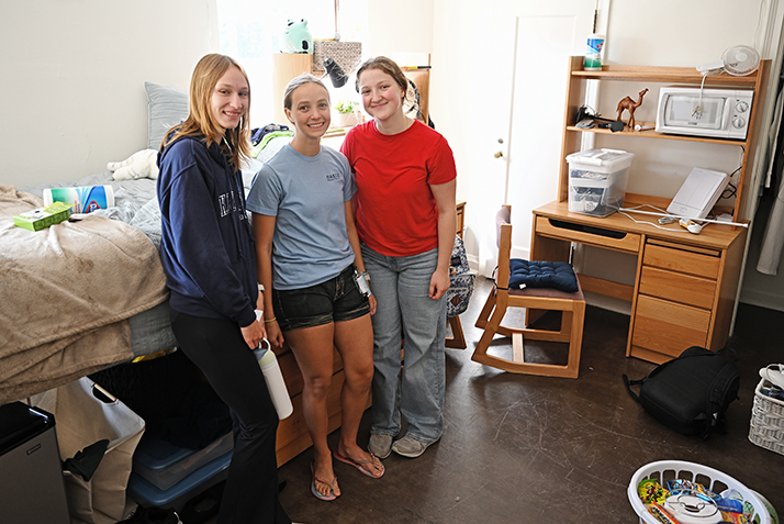 New roommates pose for a photo as they unpack and set up their new room.