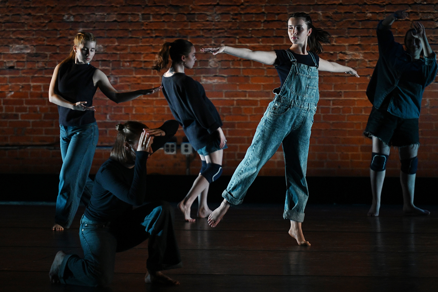 dancers in denim overalls perform on stage