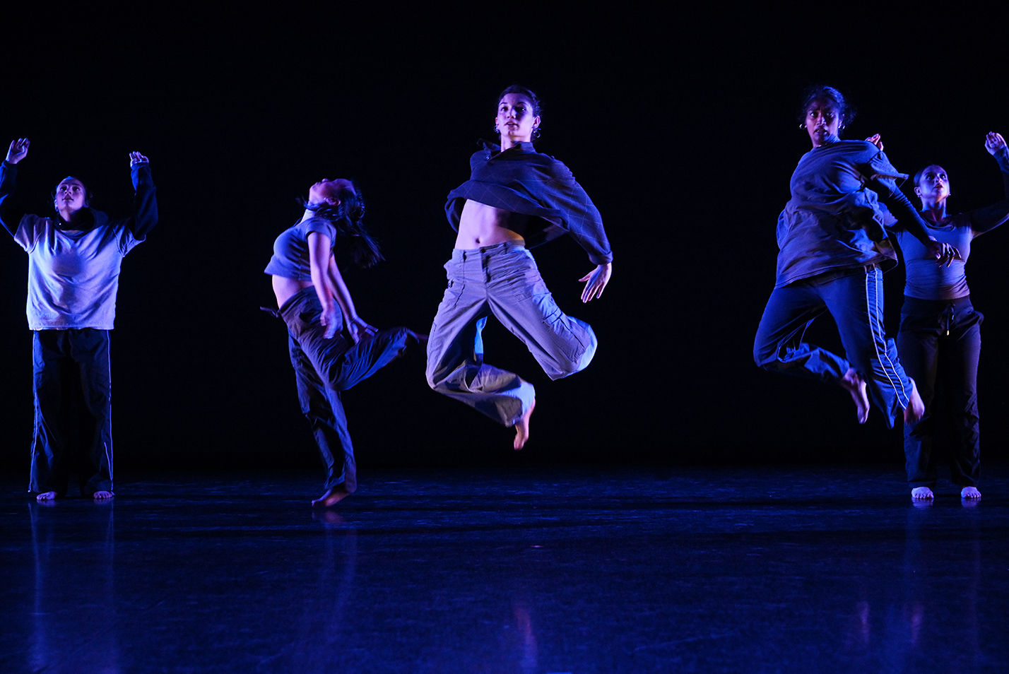 Two dancers appear to float in the air as they perform with a larger group on stage.