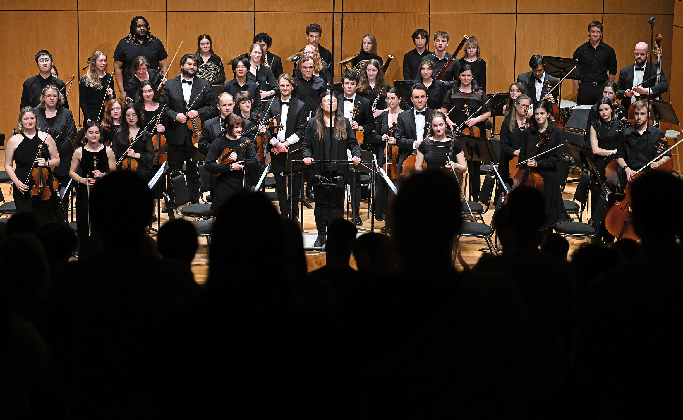 Members of an orchestra stand to take their bows at the conclusion of a concert.
