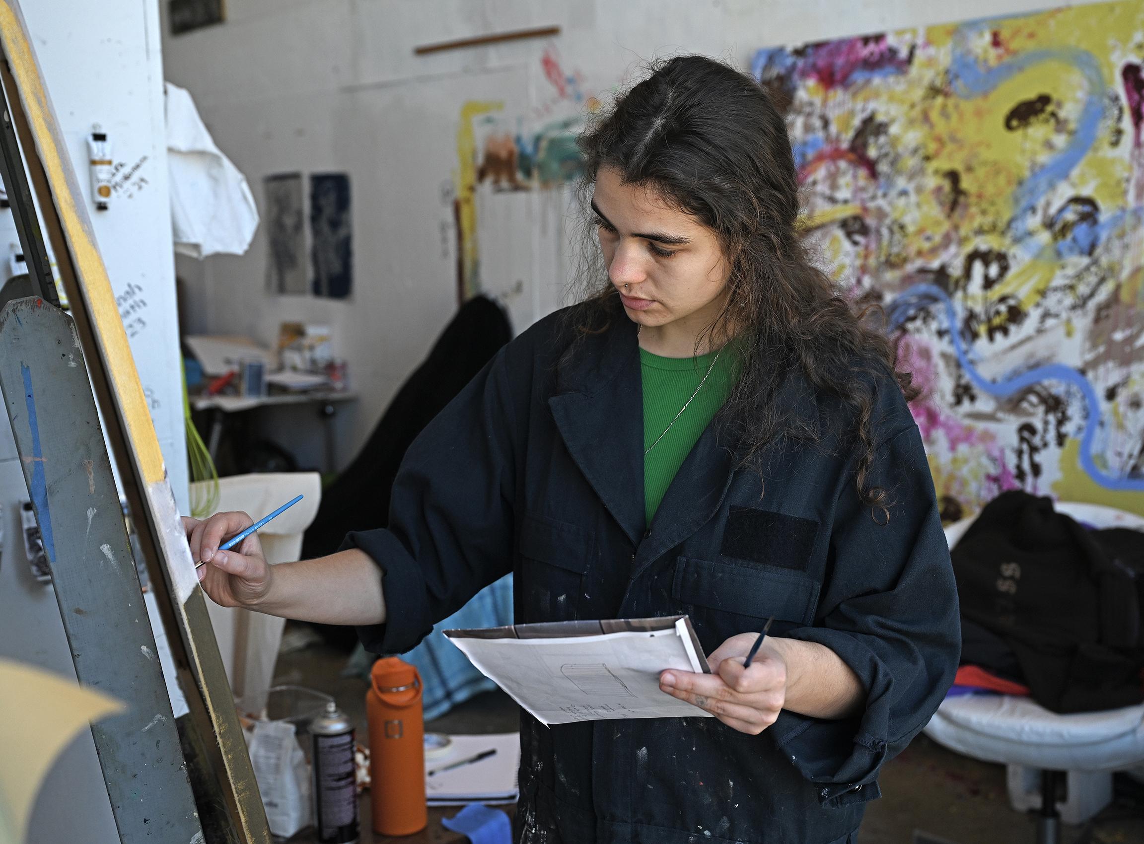 A student artist paints in oils on canvas in an art studio.