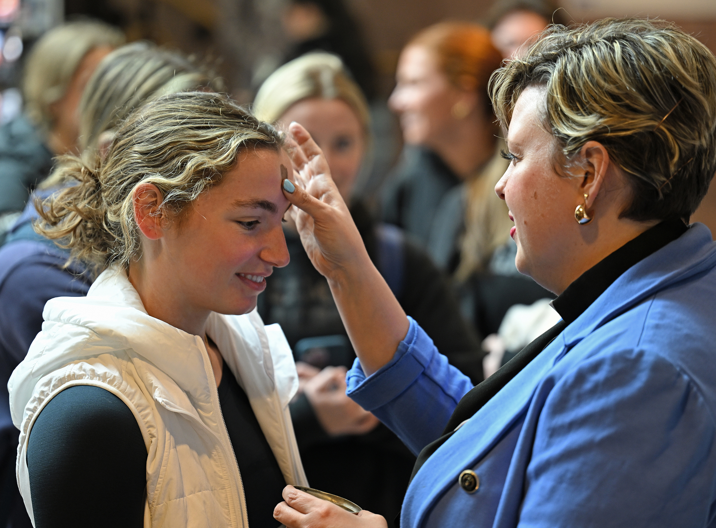 A minister offers ashes for Ash Wednesday to a group of college students.