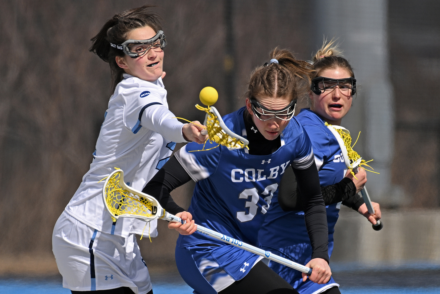 collegiate women's lacrosse players battle for possession of the ball.